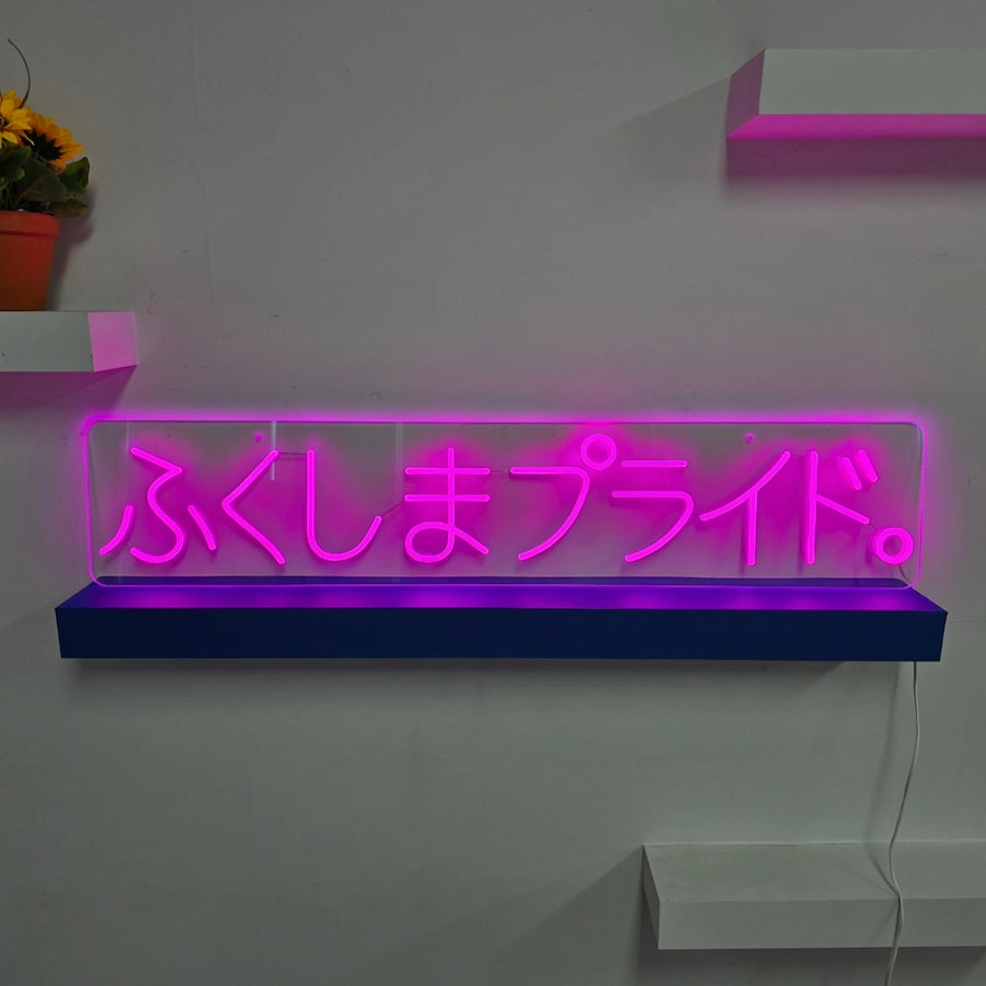 「ふくしまプライド。」の文字を鮮やかなピンクで表現したLEDネオンサイン。透明アクリル製の横長デザインで、店舗・イベント・展示スペースの装飾やアイキャッチに適した壁面設置タイプ。