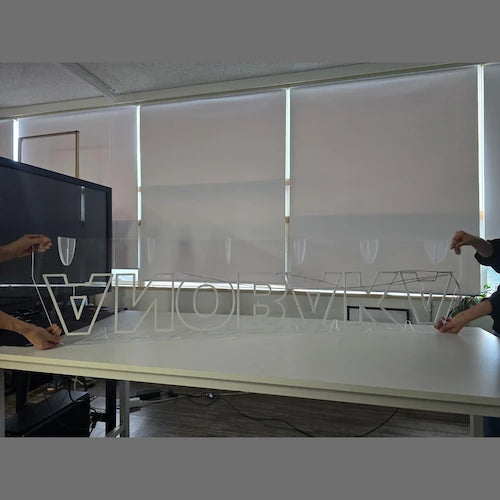 ANOBAKAロゴのLEDネオンサイン看板。アクリル立て台で立つスタンドタイプを両側から持っている様子。