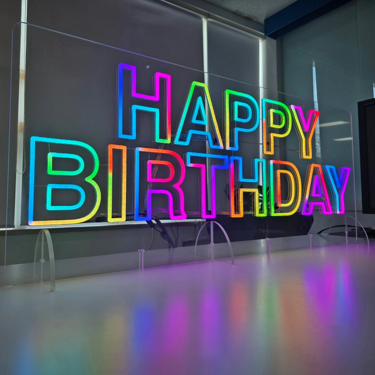 HAPPY BIRTHDAYロゴのネオン看板。リモコンによる変色機能付き。壁面に吊り下げての使用も可能にするため、アクリル板上部に２カ所吊り下げ穴を加工。