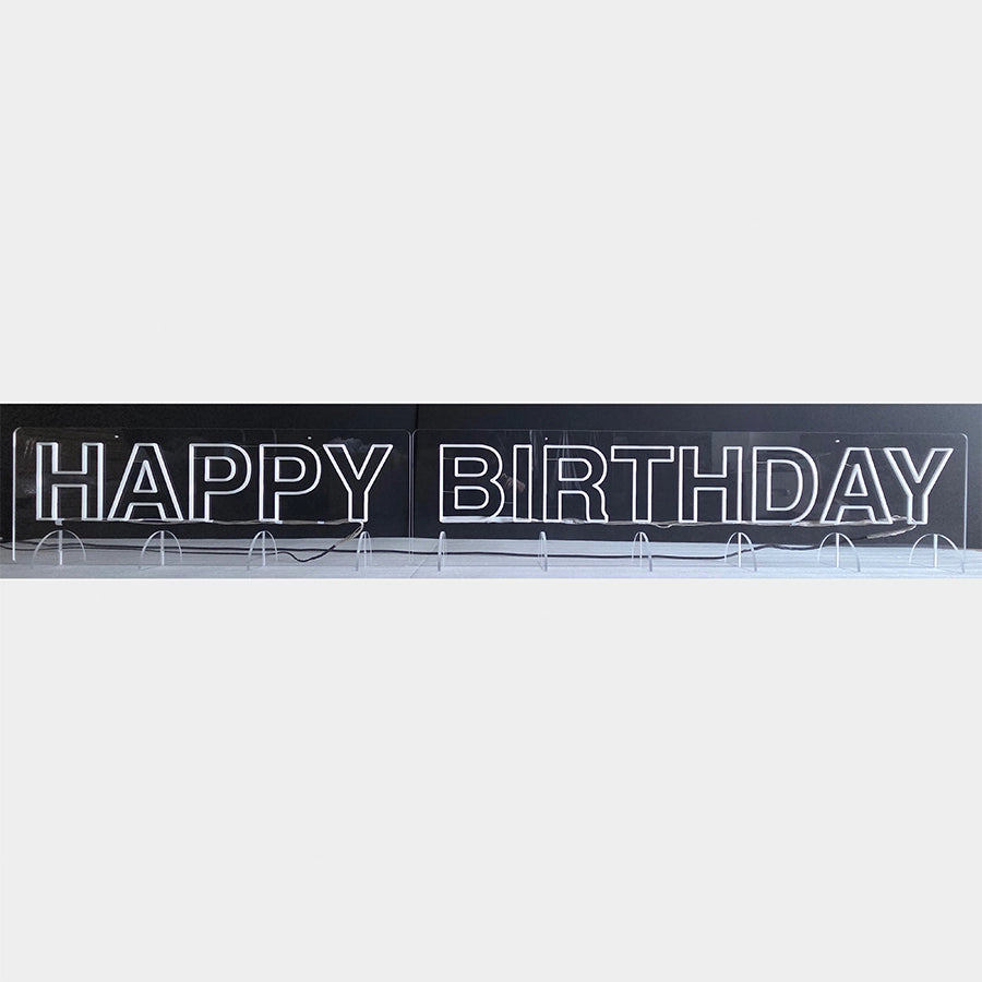 HAPPY BIRTHDAYロゴのネオン看板。長尺のため、アクリル板を2分割で製作し、透明アクリル製のスタンド(計10個)で自立させている。