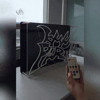 KMNPARTYロゴのLEDネオンサイン看板。金属スペーサーと２枚のアクリル板で立つスタンドタイプとリモコンを消灯時に左から撮影した写真。