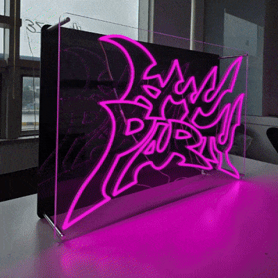 KMNPARTYロゴのLEDネオンサイン看板。金属スペーサーと２枚のアクリル板で立つスタンドタイプを点灯時に左から撮影した写真。