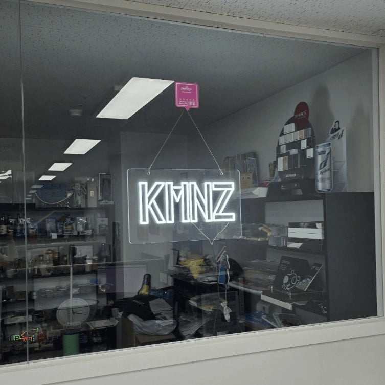 KMNZロゴのLEDネオンサイン看板。窓ガラスタイプをガラスに設置して左から見た遠景アングル。