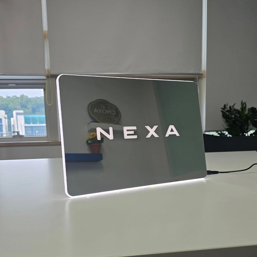NEXAロゴをホワイトカラーで表現したFFL(自由形状曲線ライト)特注LED看板。長方形カットとミラー仕上げを採用し、シンプルで高級感のあるデザイン。
