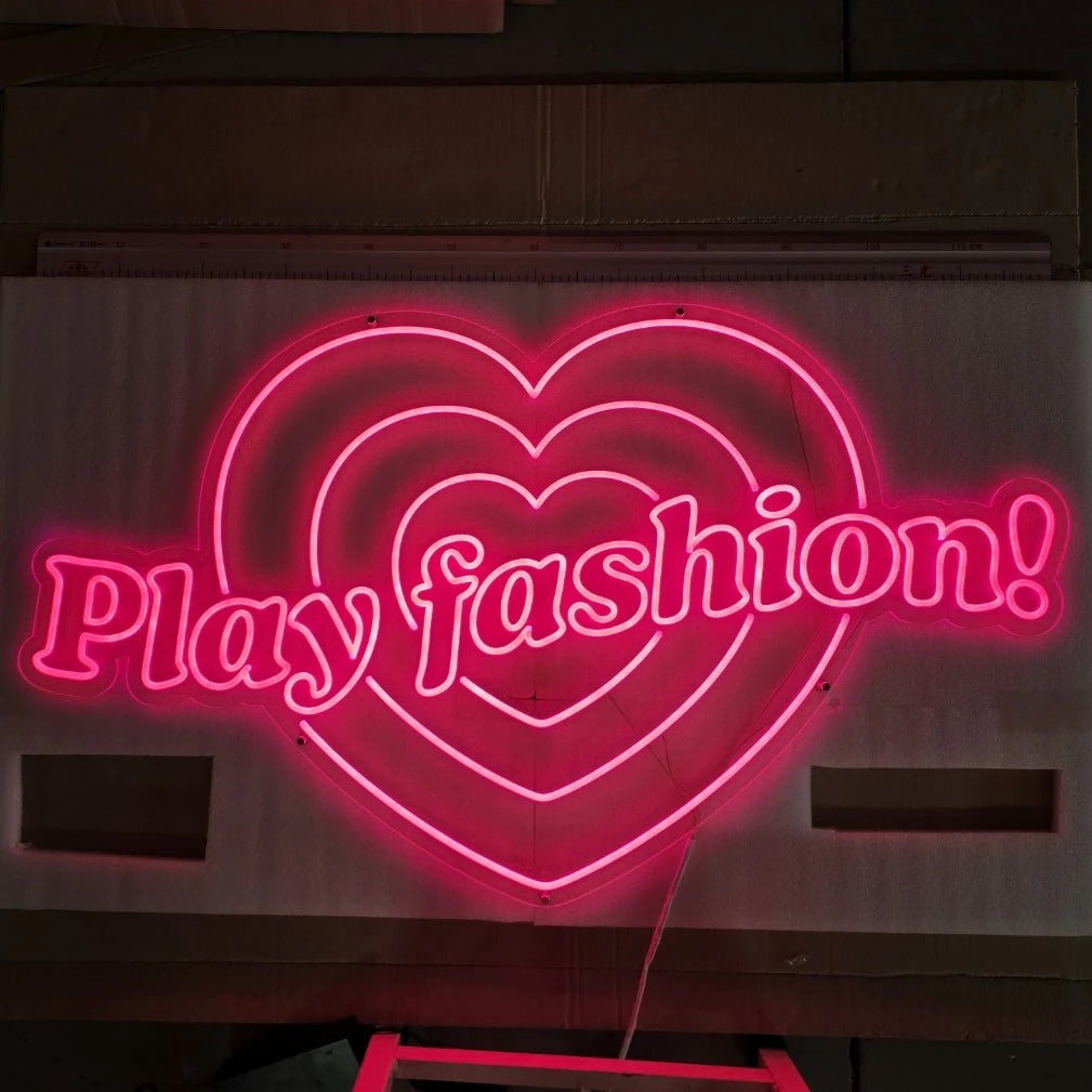 Play fashionロゴのLEDネオンサイン看板。屋内壁面タイプを暗所で低輝度に点灯し、正面から撮影した写真。
