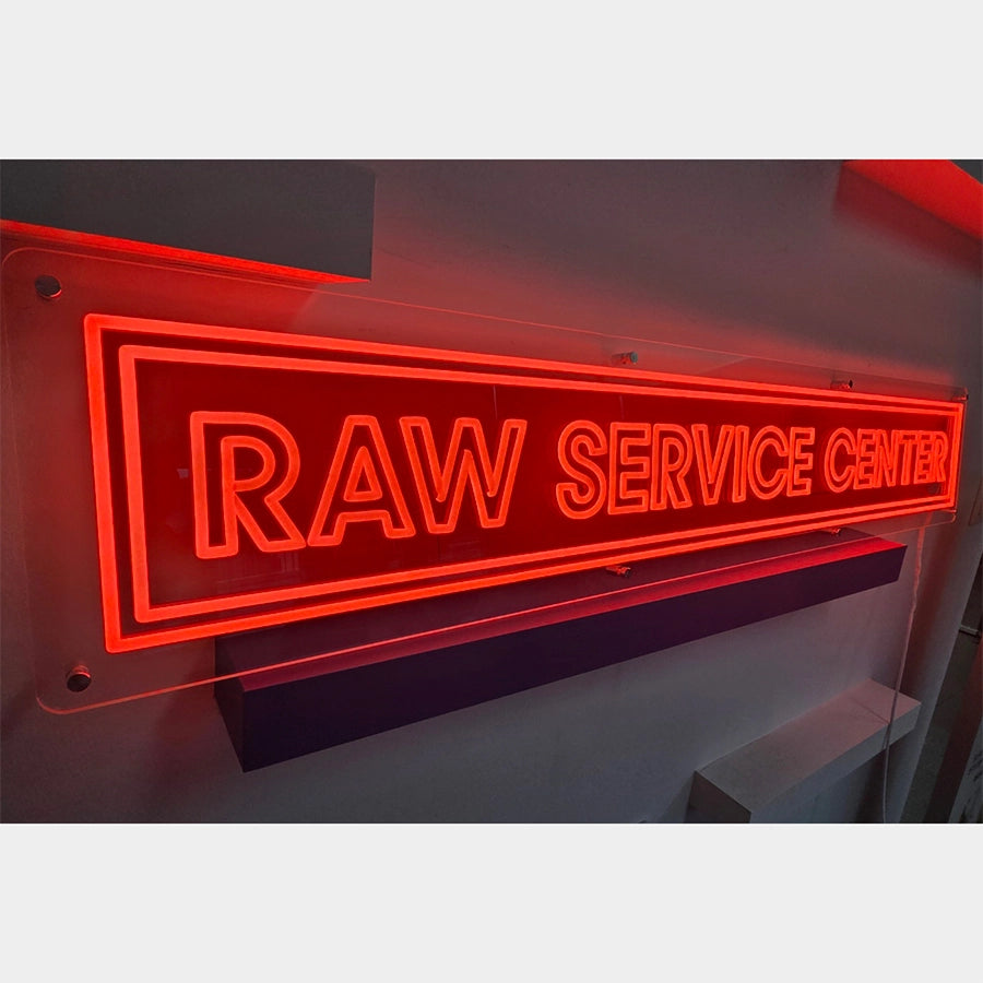 RAW SERVICE CENTERロゴのネオン看板。点灯した状態のネオン製品全体を側面から撮影したビジュアル。電源コードは右下から出る仕様。
