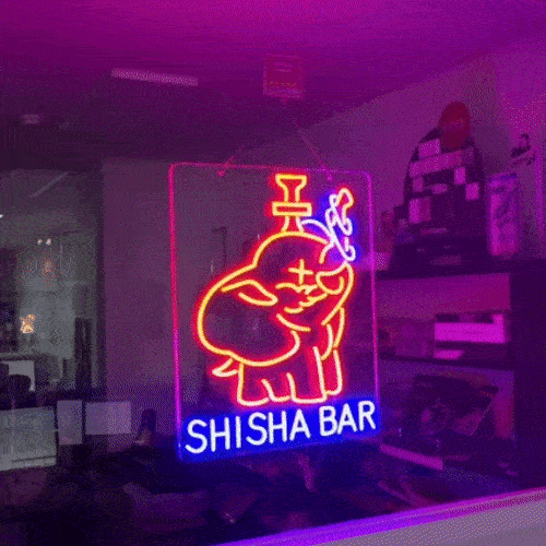 SHISHABARロゴのLEDネオンサイン看板。暗い室内で窓ガラスタイプをガラスに設置して左から見たアングル。