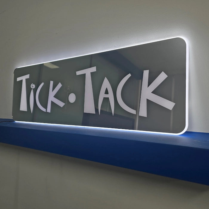 TiCK・TACKロゴのFFL看板(壁面設置タイプ)。背面収納ワイヤー仕様でワイヤーを露出せず壁掛けが可能。
