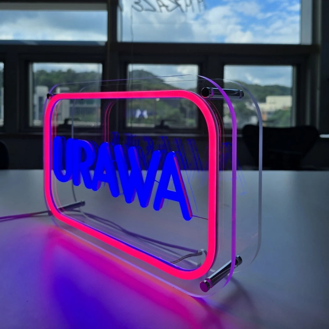 URAWAロゴのLEDネオンサイン看板。金属スペーサーと２枚のアクリル板で立つスタンドタイプを点灯時に右斜めから撮影したアングル。