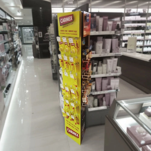 ヴァセリンとカーメックスを混合陳列したリップグロスの大型ディスプレイスタンド,フォーメックスの他に多様な素材,ショッピングモール,フランチャイズドラッグストア,商業施設