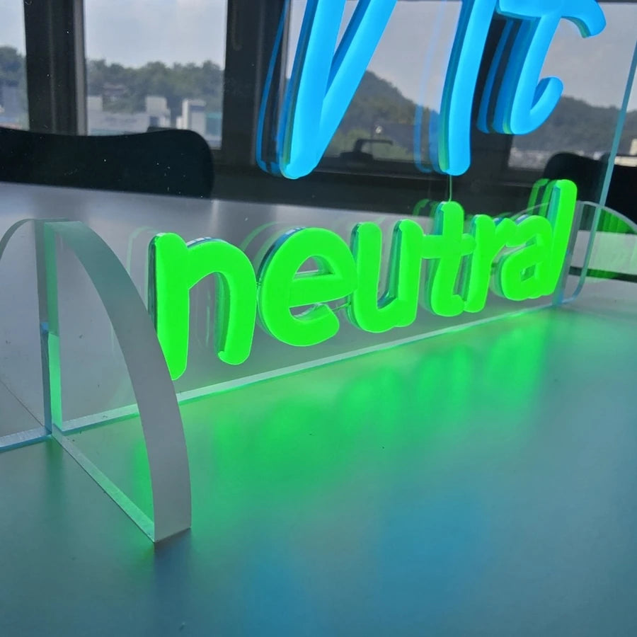 nt neutralロゴのLEDネオンサイン看板。アクリル立て台で立つスタンドタイプの下部をクローズアップした写真